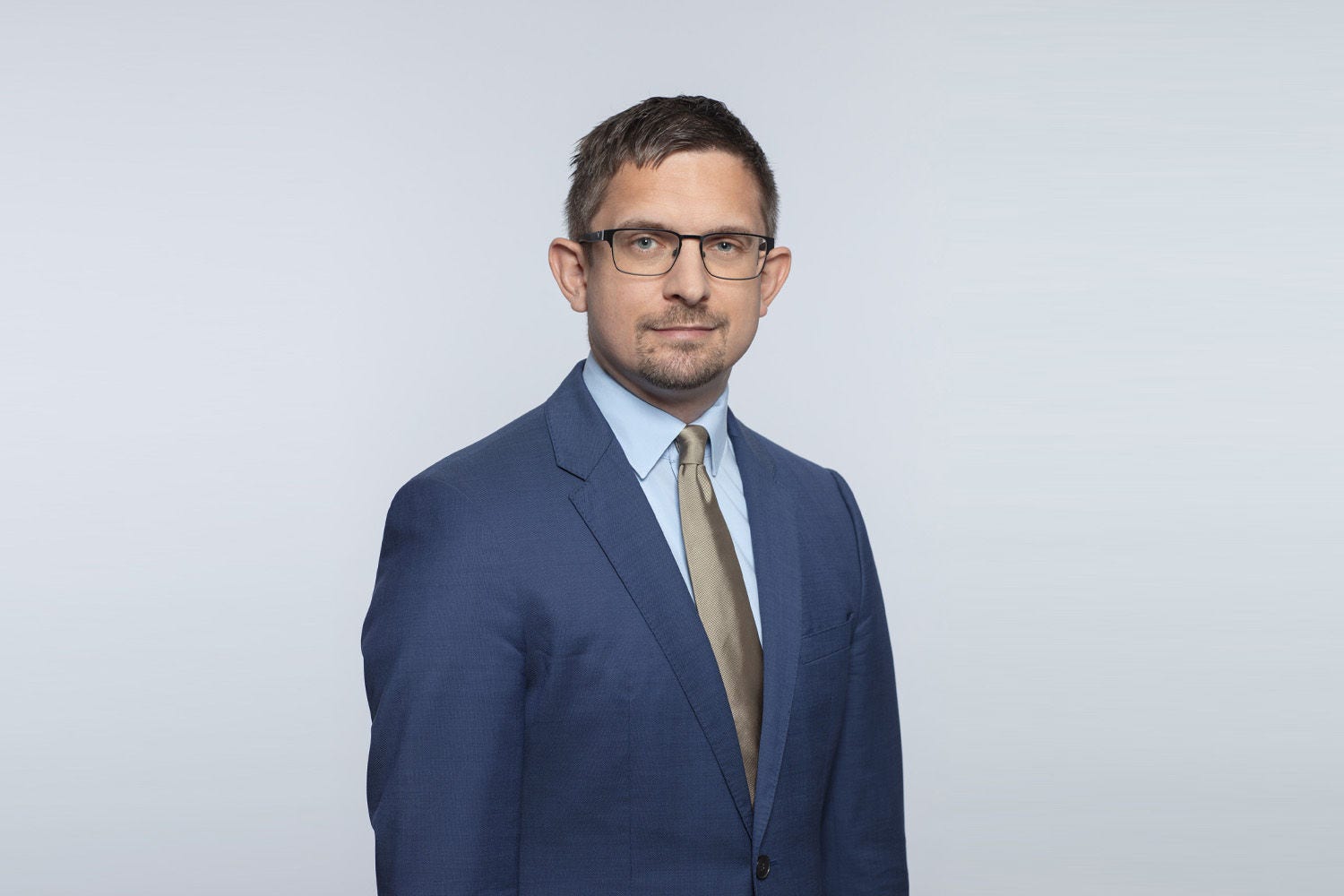 Porträt von Andreas Theuerer vor einer hellgrauen Wand