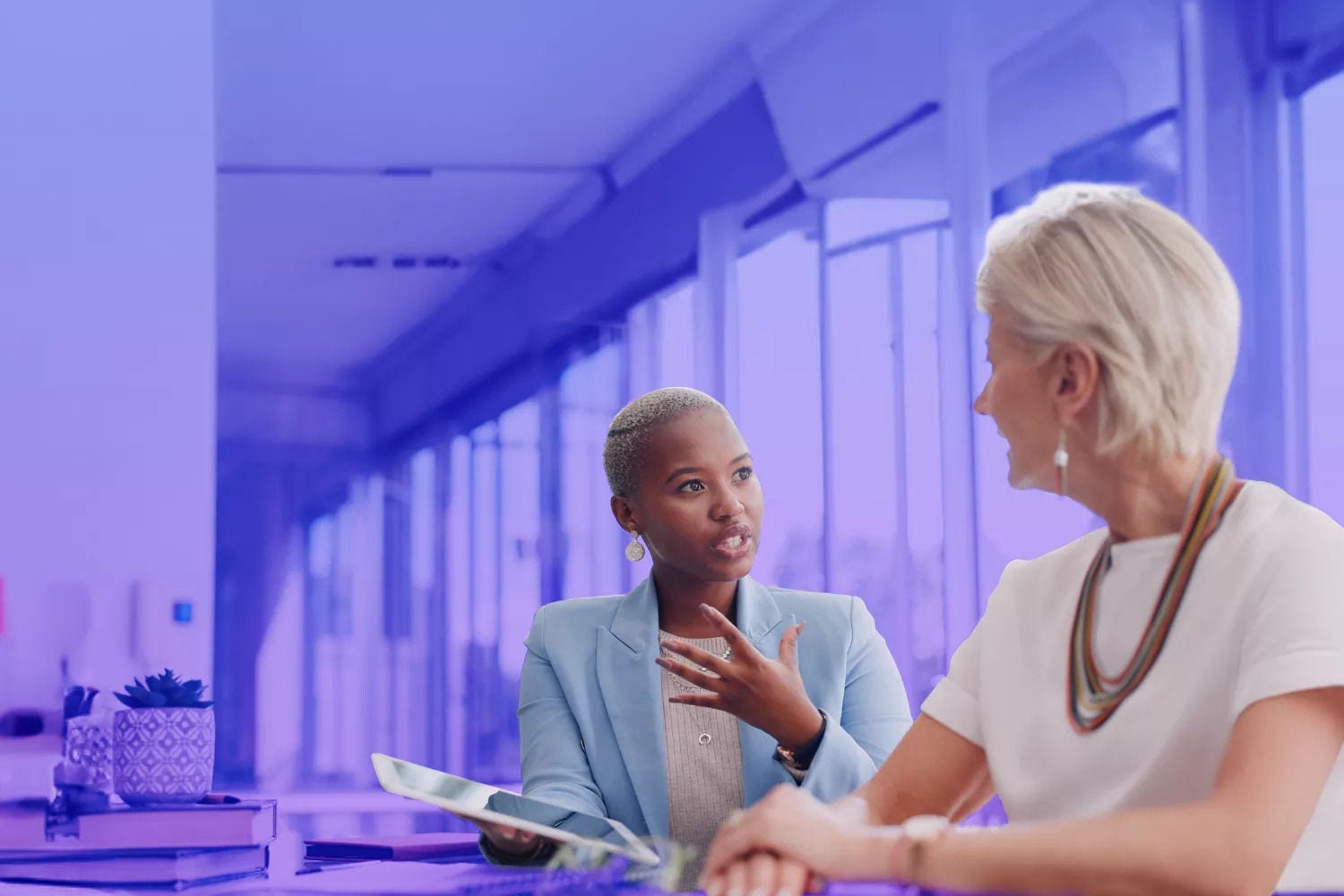 Mulheres discutindo ideias num escritório e uma delas com um tablet na mão