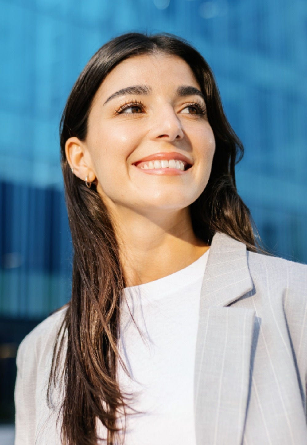 A person smiling with a glass building in the background