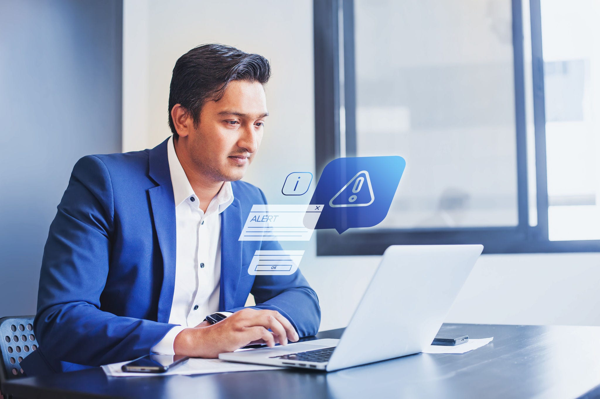 Indian man receiving alert notification in financial fraud protection software on his computer Indian man receiving alert notification in financial fraud protection software on his computer