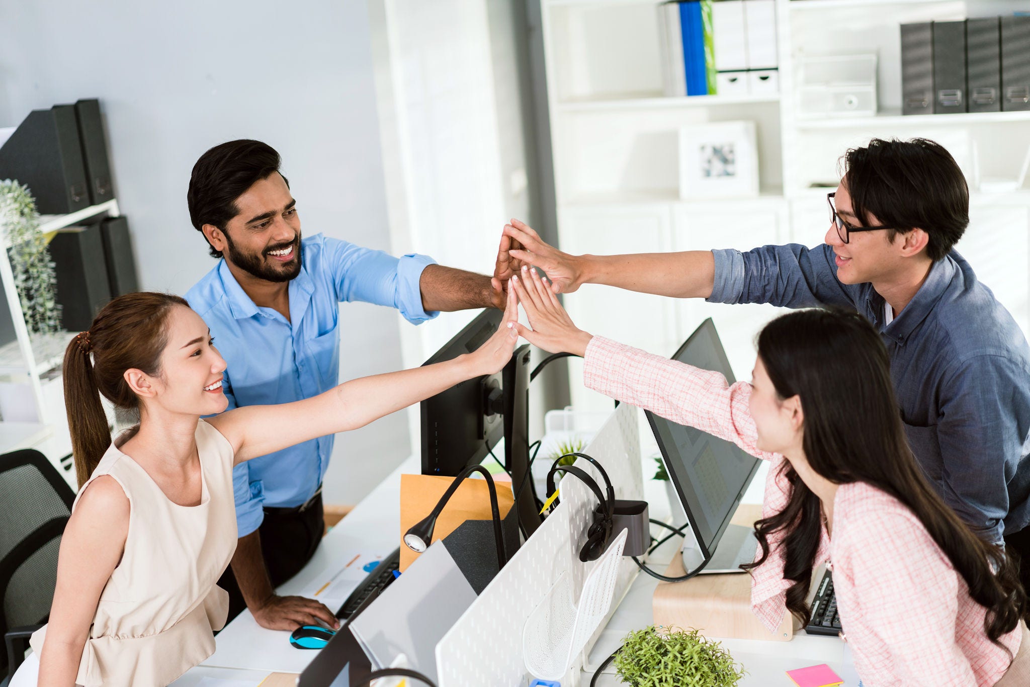 Team of young Asian, Indian and Thai entrepreneurs and startup have business meeting, encouraging and high five each other for good energy to accomplish successful marketing plan. Diversity of team. Team of young Asian, Indian and Thai entrepreneurs and startup have business meeting, encouraging and high five each other for good energy to accomplish successful marketing plan. Diversity of team.