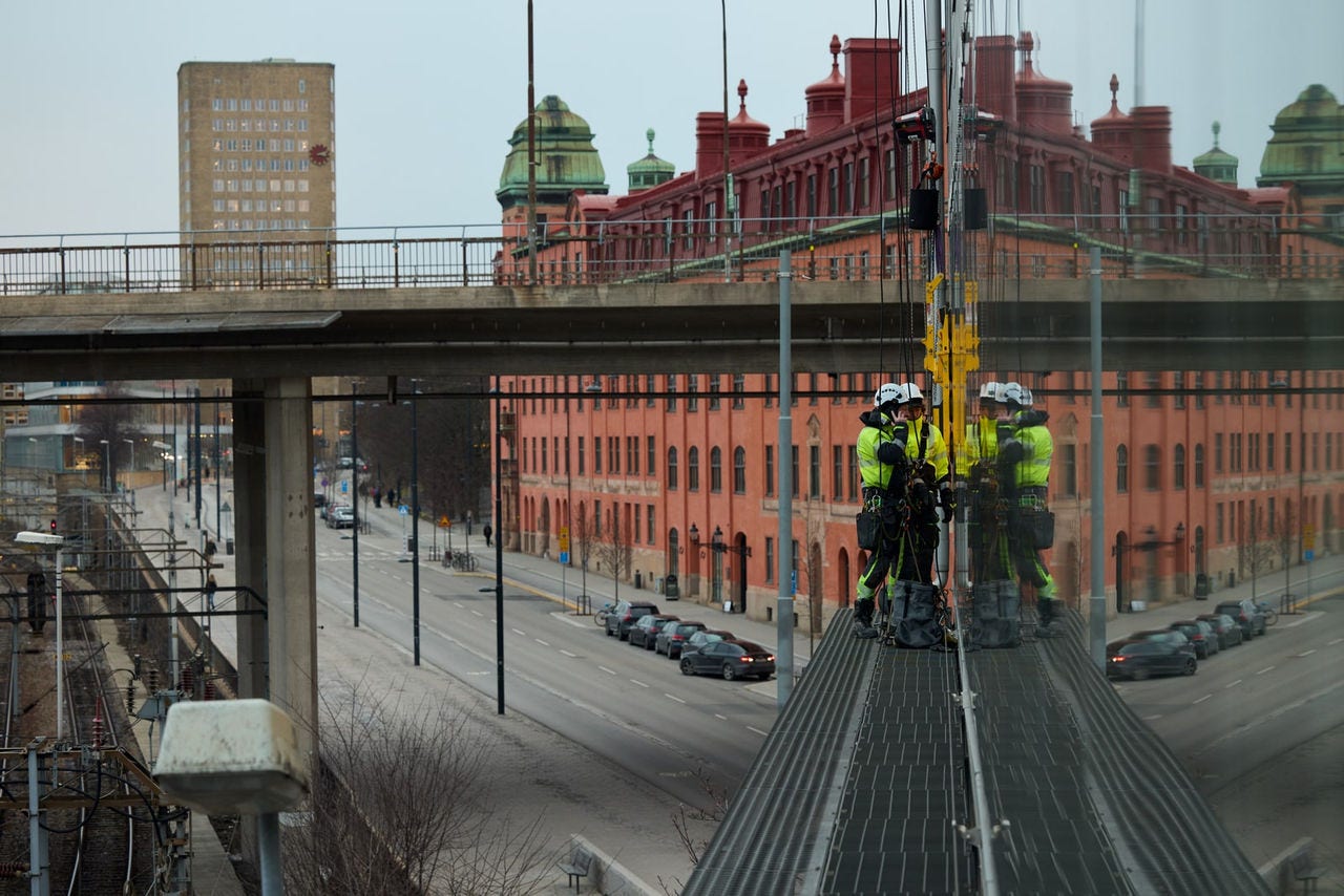 Arbeidere klatrer på en glassfasade
