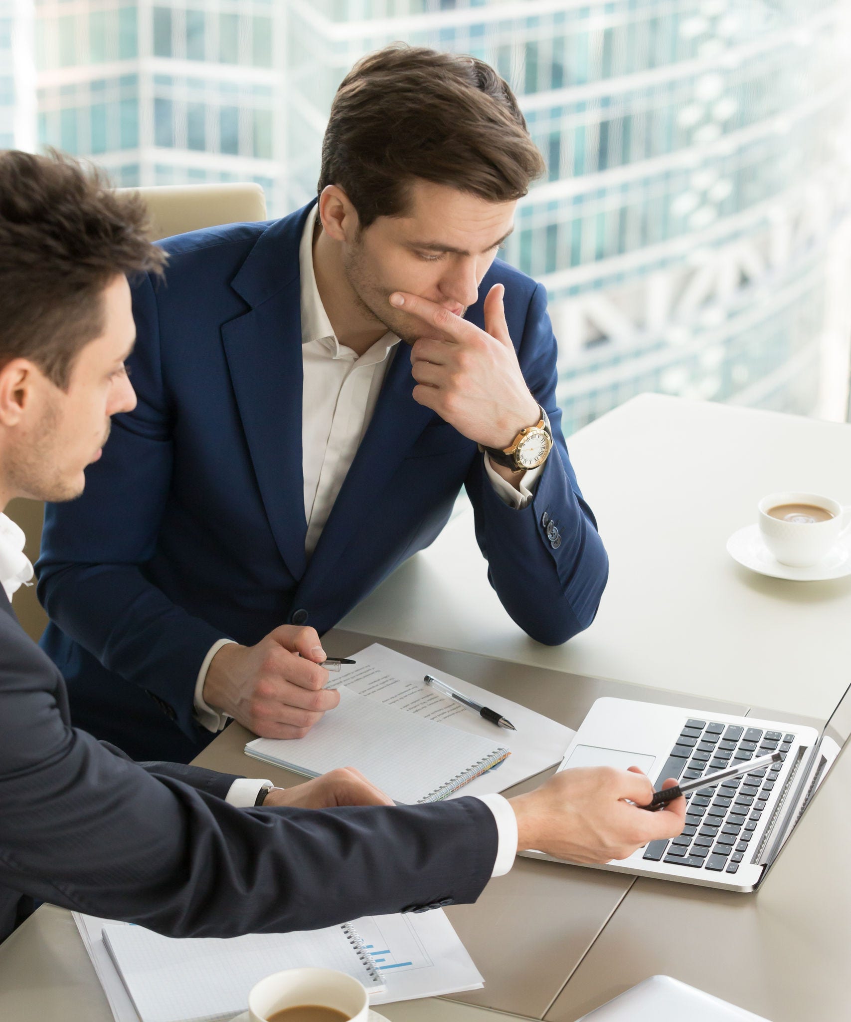 Business partners using laptop while working together on important corporate project in office. Businessman attentively listening to adviser Investment specialist making presentation of promising deal