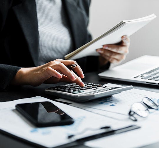 Close up of businesswomen or accountant using calculator calculate while working analytic business report on the workplace, Planning financial and accounting concept.