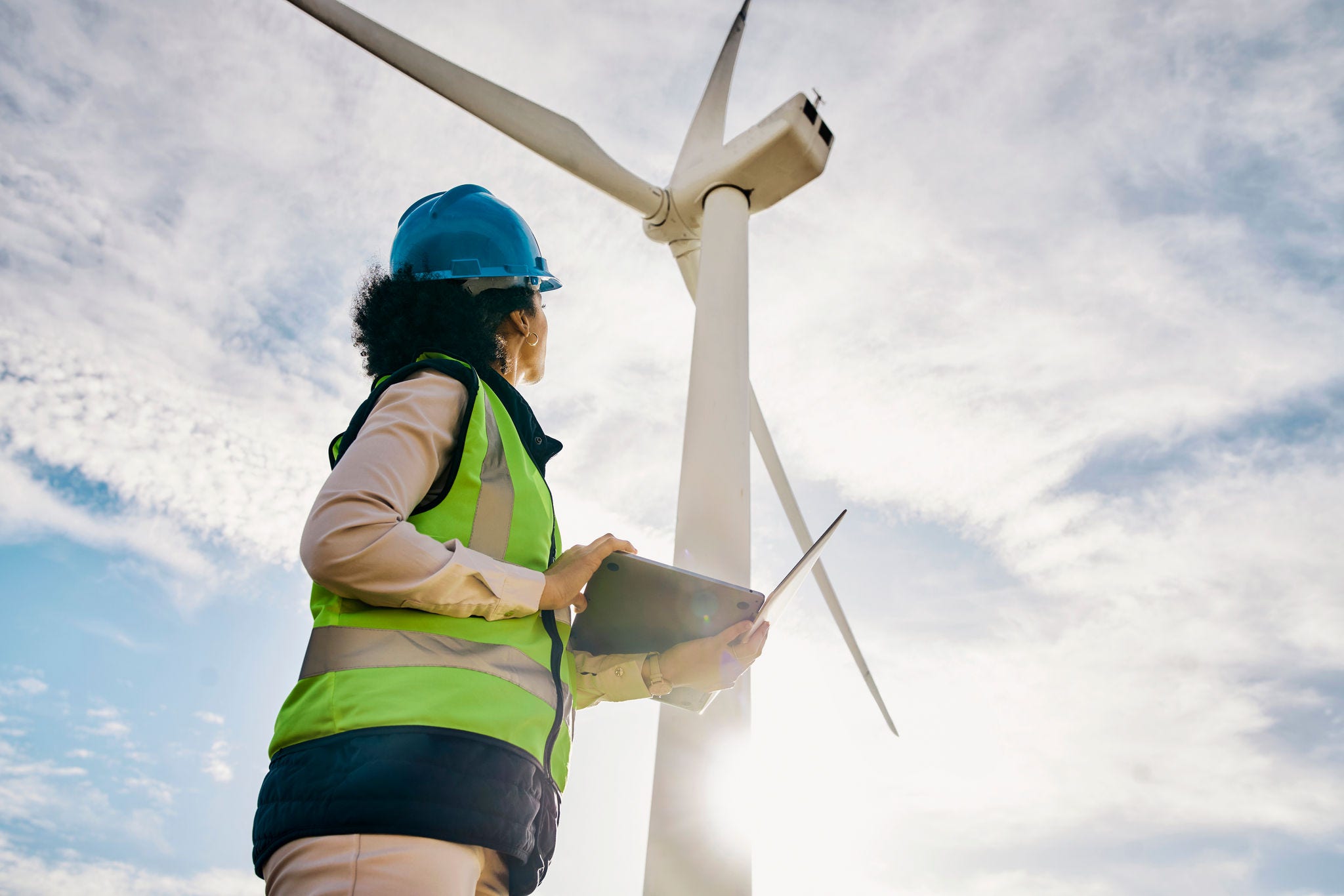 Engineer woman, wind turbine and laptop on farm for renewable energy, power and electricity. Electrician or technician in nature for windmill, eco and green environment inspection and maintenace