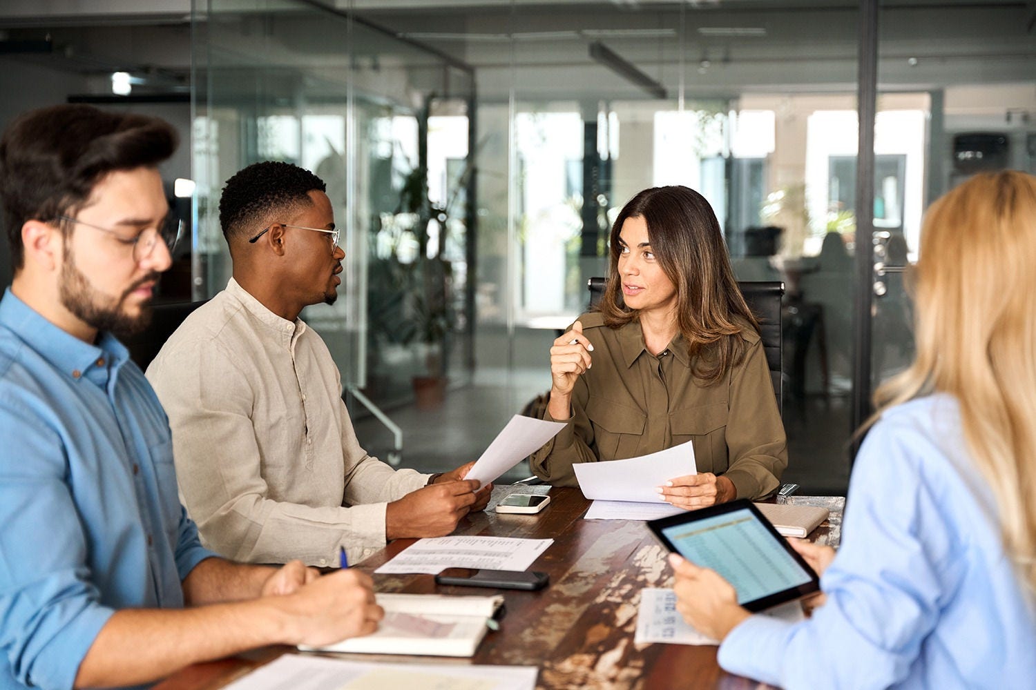 People sat around a table holding documents whilst in conversation
