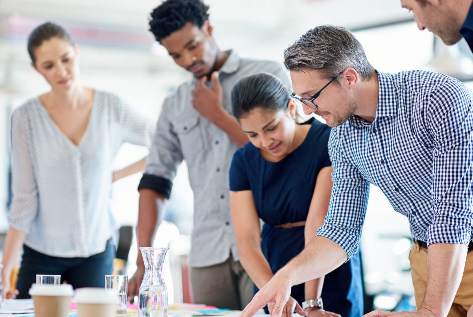 Mature man describing a plan of action to his diverse creative team.