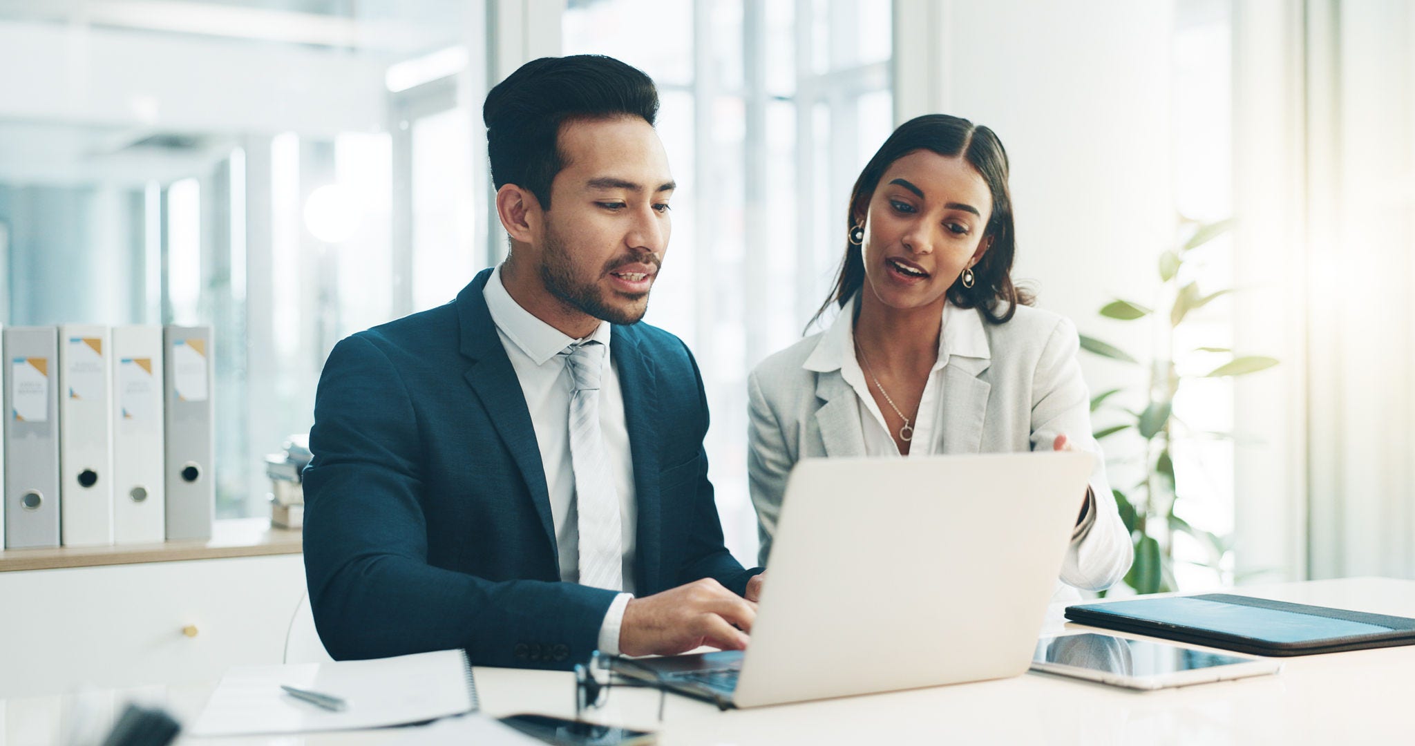 Businessman, laptop and team in finance discussion, project planning or schedule at office. Asian man and business woman working on computer for corporate statistics or financial plan at workplace.