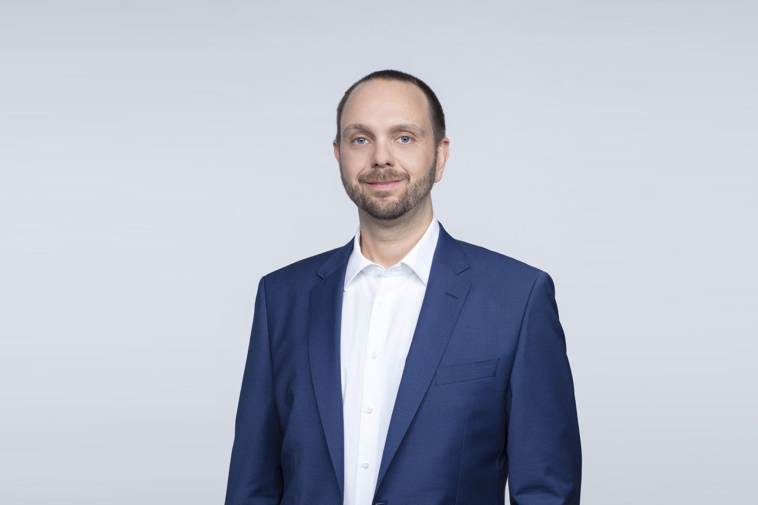 Porträt von Daniel Kroiss vor einer hellgrauen Wand