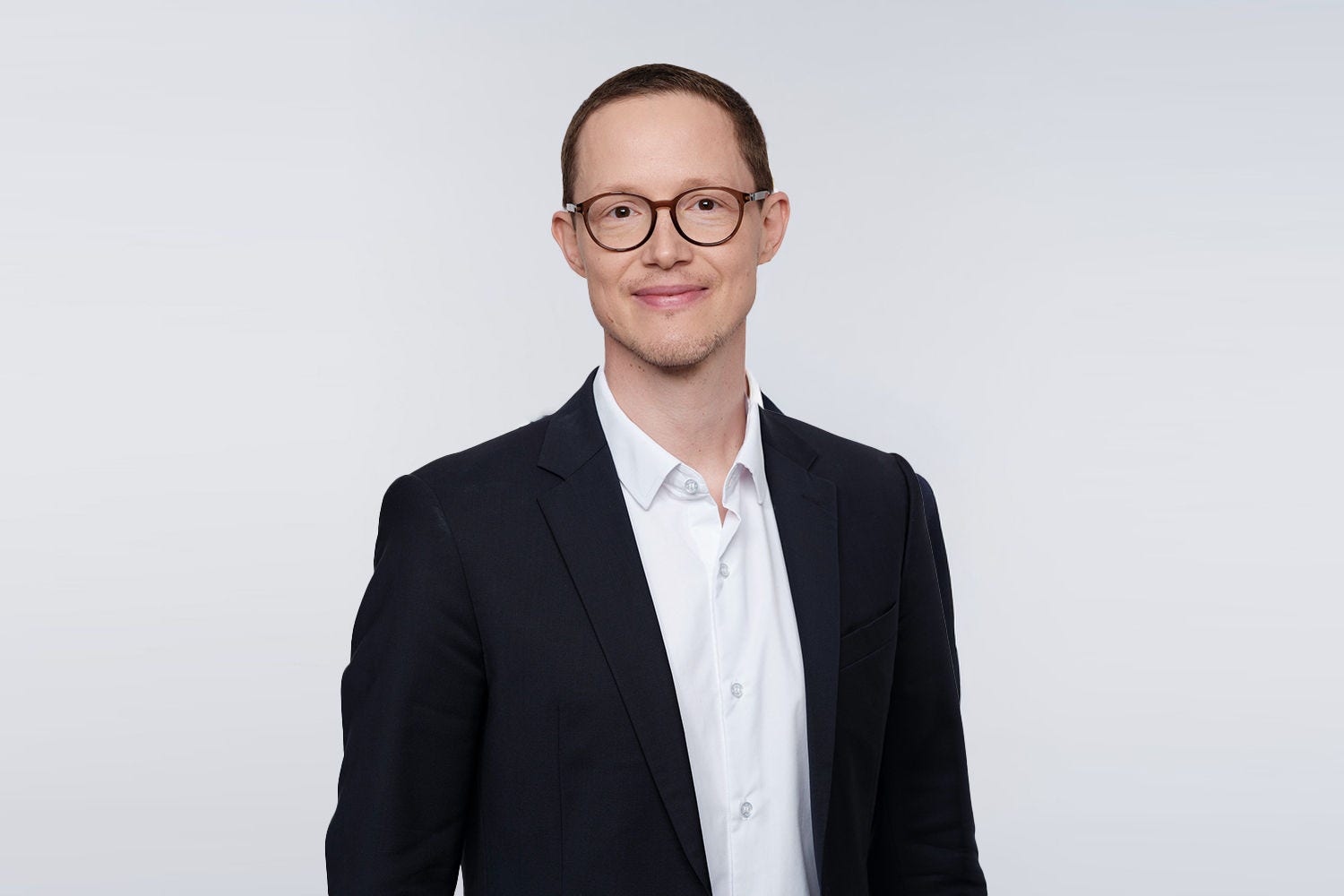 Porträt von David Mayer vor einer grauen Wand