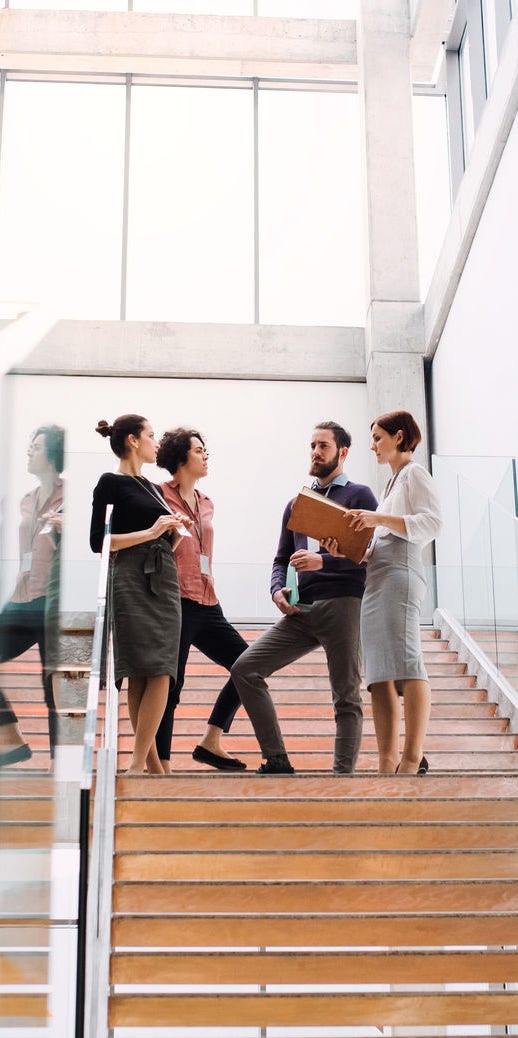 A group of young businesspeople standing on a staircase, talking.