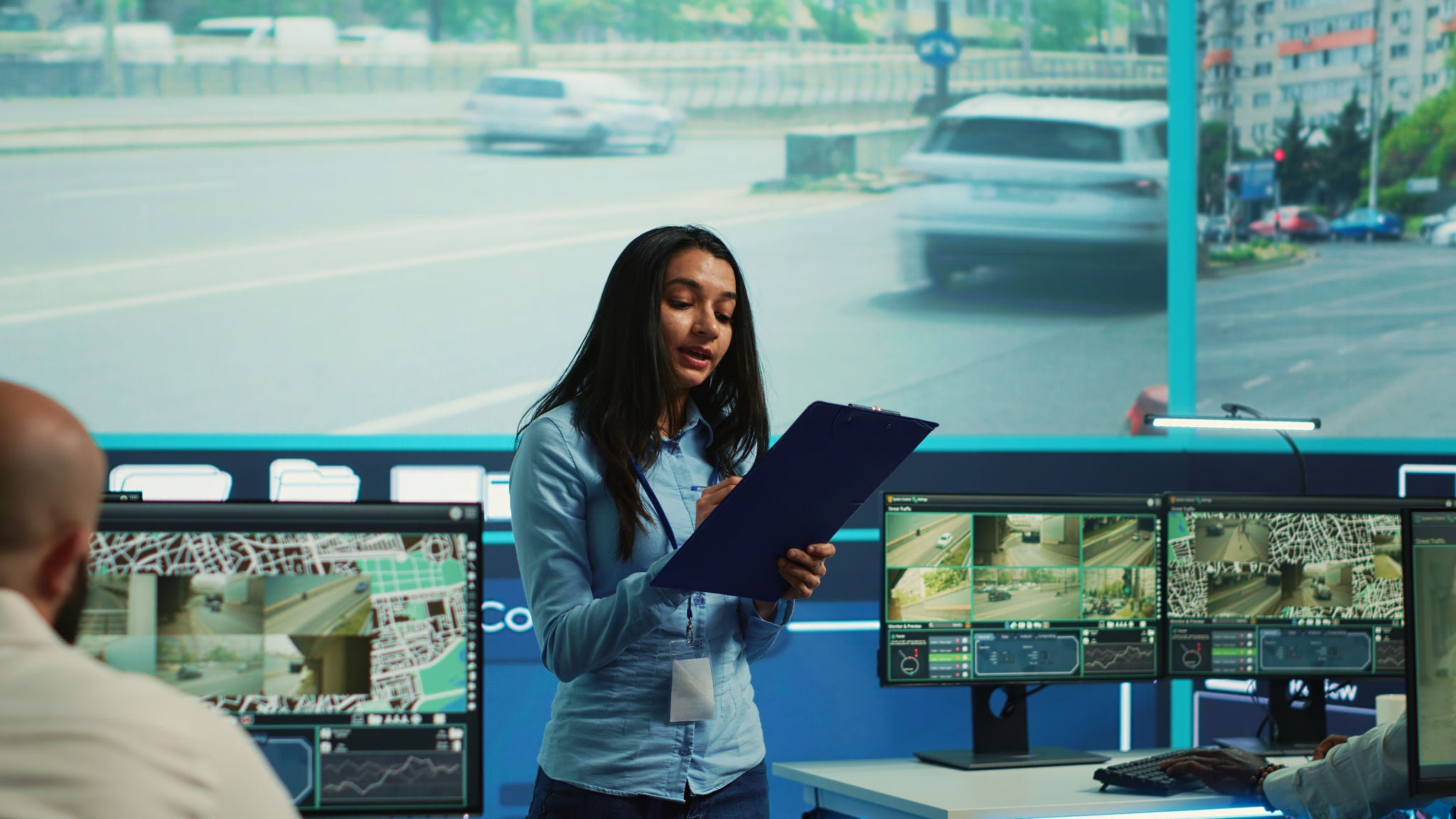 Indian supervisor leads her team to monitor the surveillance video footage and CCTV cameras to learn about urban traffic dynamics. Diverse people working on public safety. Camera A.