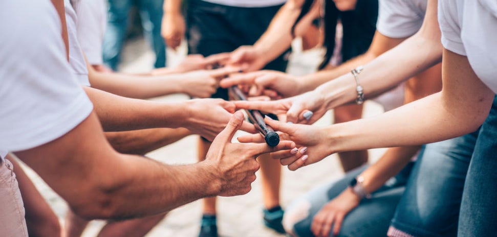 teambuilding activity with stick and hands colleagues