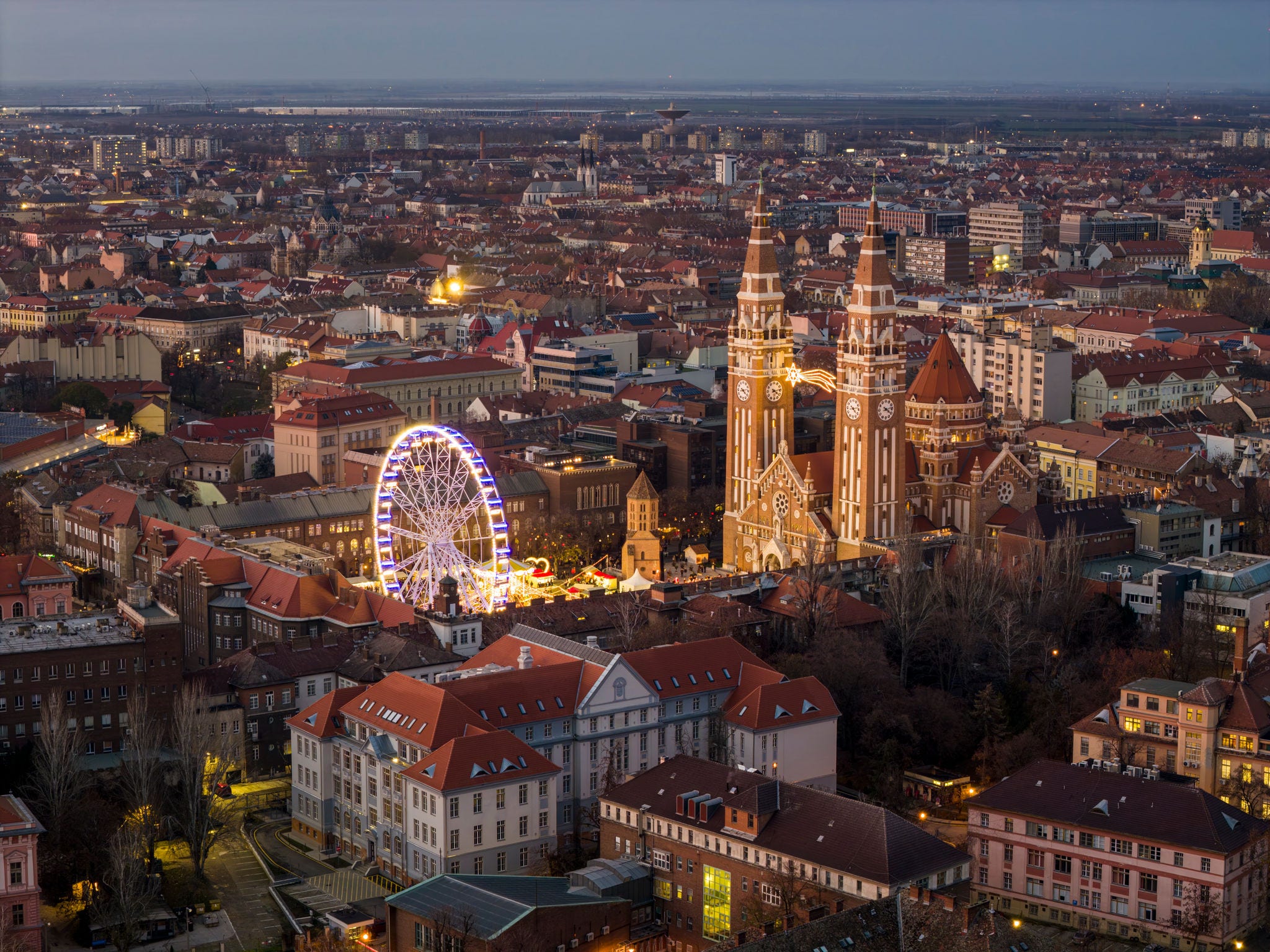 Szeged, Hungary, Giant christmas market at next to Szeged cathedral. Hungarian foods, drinks, presents and gifts. Giant labirintyh and ferris whhel for children