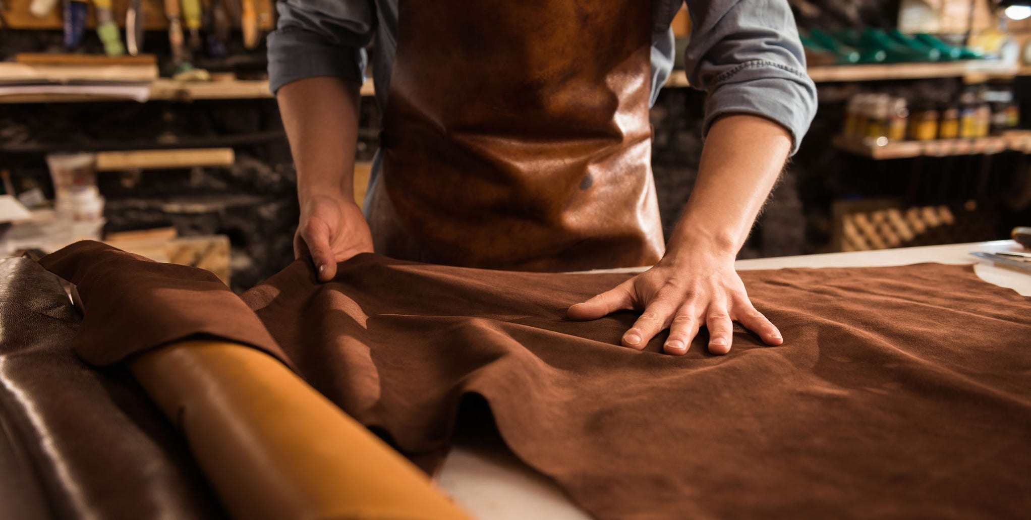 Close up of a cobbler working with leather textile at his workshop