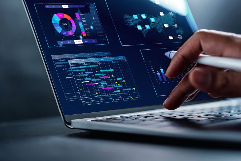 A person holding a pen clicking on a keyboard of a laptop with data showing on the screen