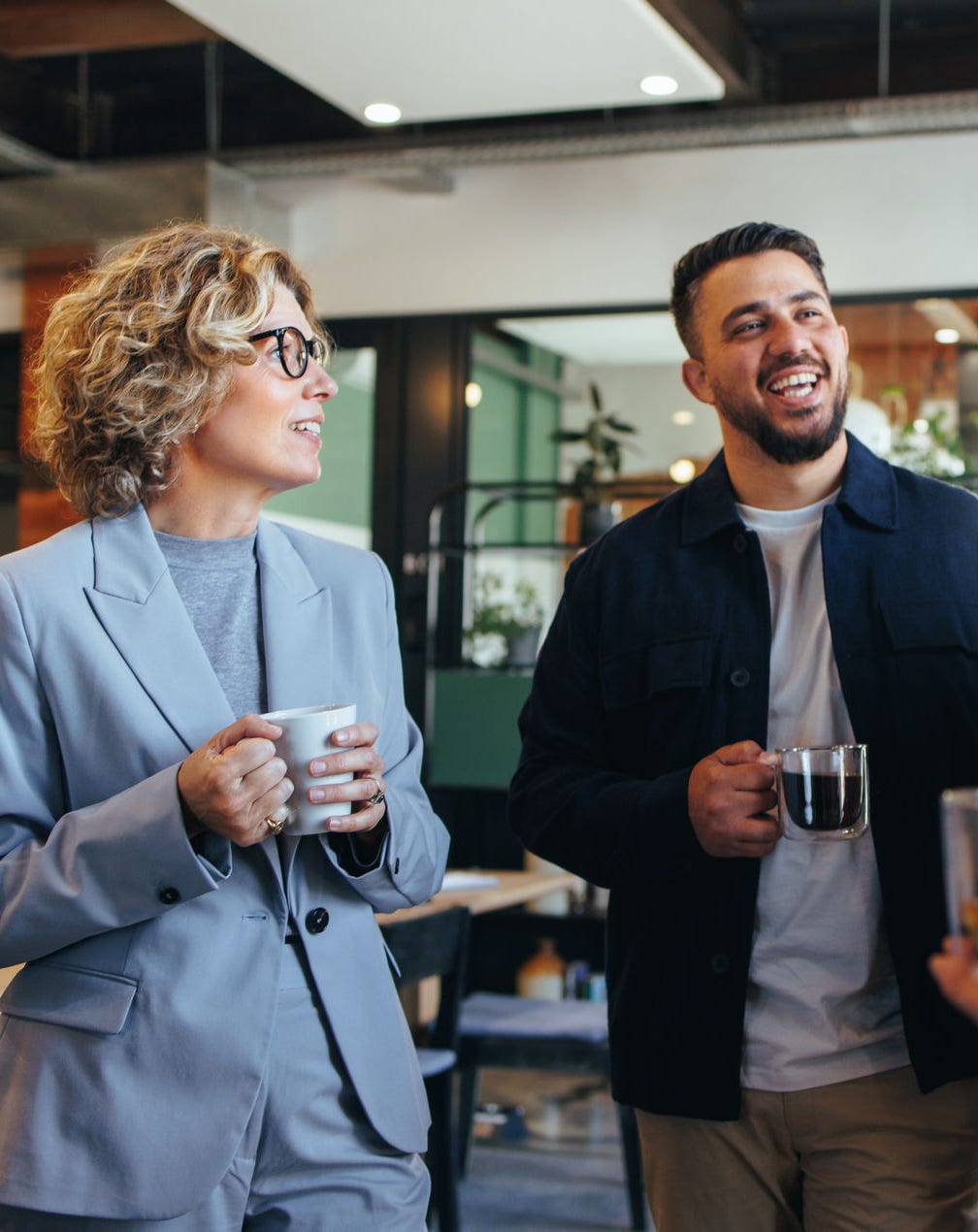 Happy colleagues having a coffee break in an office. Group of business people having a conversation in a workplace. Business professionals working in a startup.