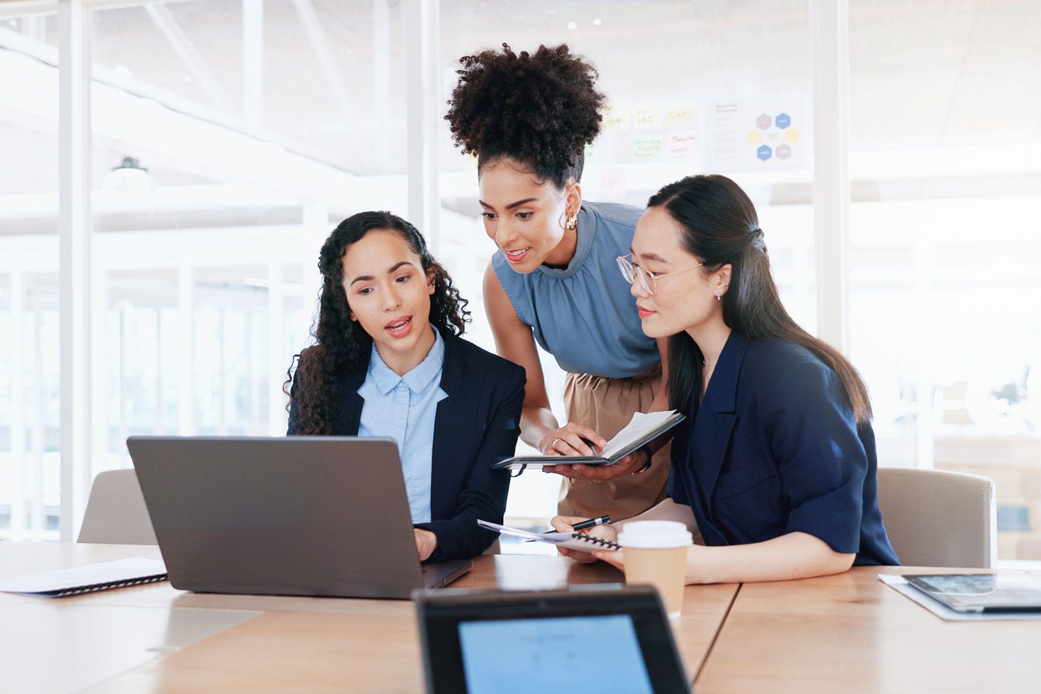 Business women, laptop and collaboration in office for marketing management, leader innovation or strategy research. Team meeting, employee support and tech manager or leadership idea discussion