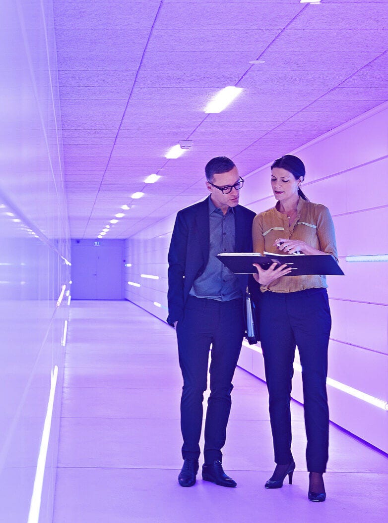 Duas pessoas a visualizar resultados numa capa num corredor iluminado