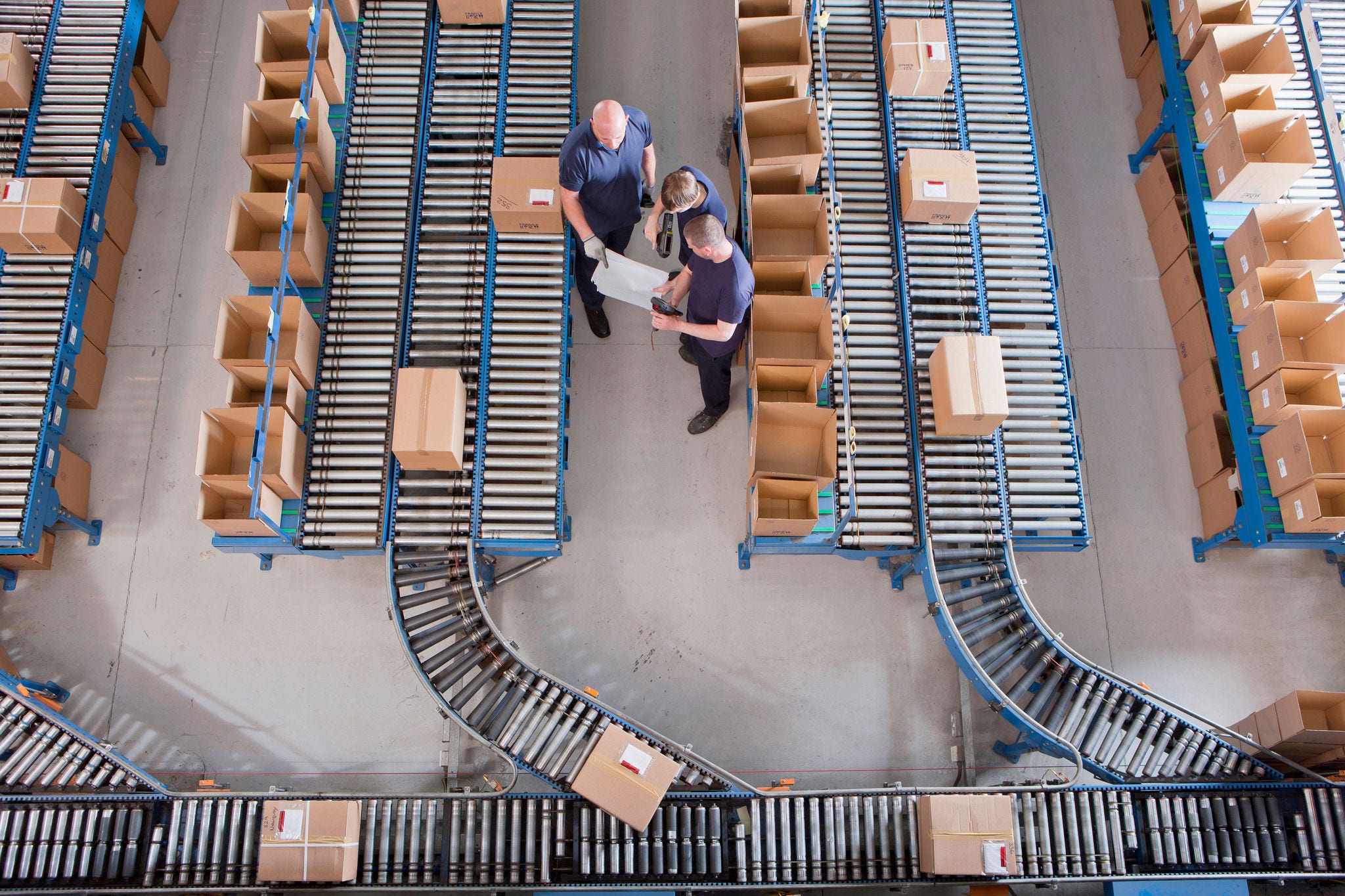 Workers in supply chain Workers meeting among boxes on conveyor belts in distribution warehouse