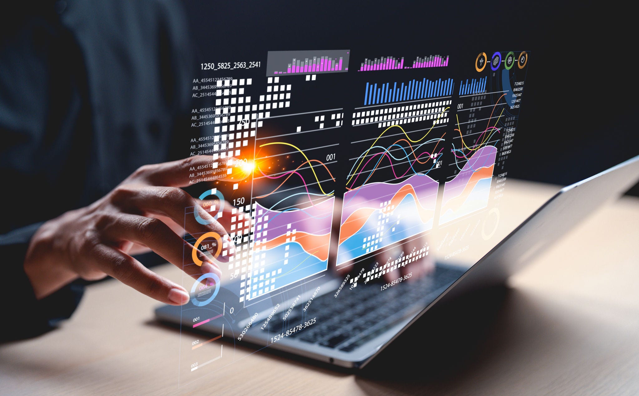 A hand interacts with holographic data visuals above a laptop, showcasing modern technology and data analysis.; Shutterstock ID 2604378995; purchase_order: 