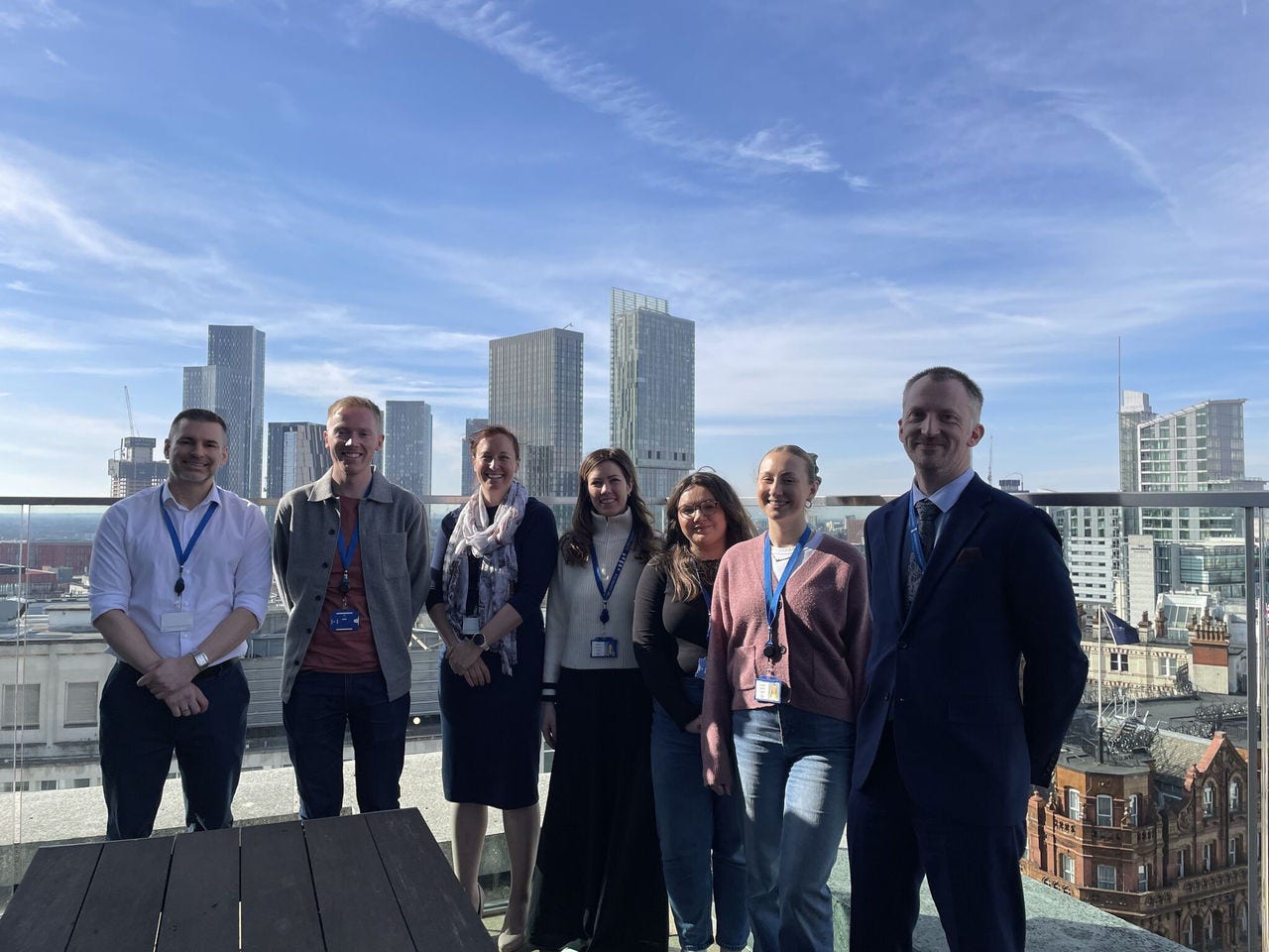 A group of KPMG colleagues stood in an outside area with a city skyline in the background