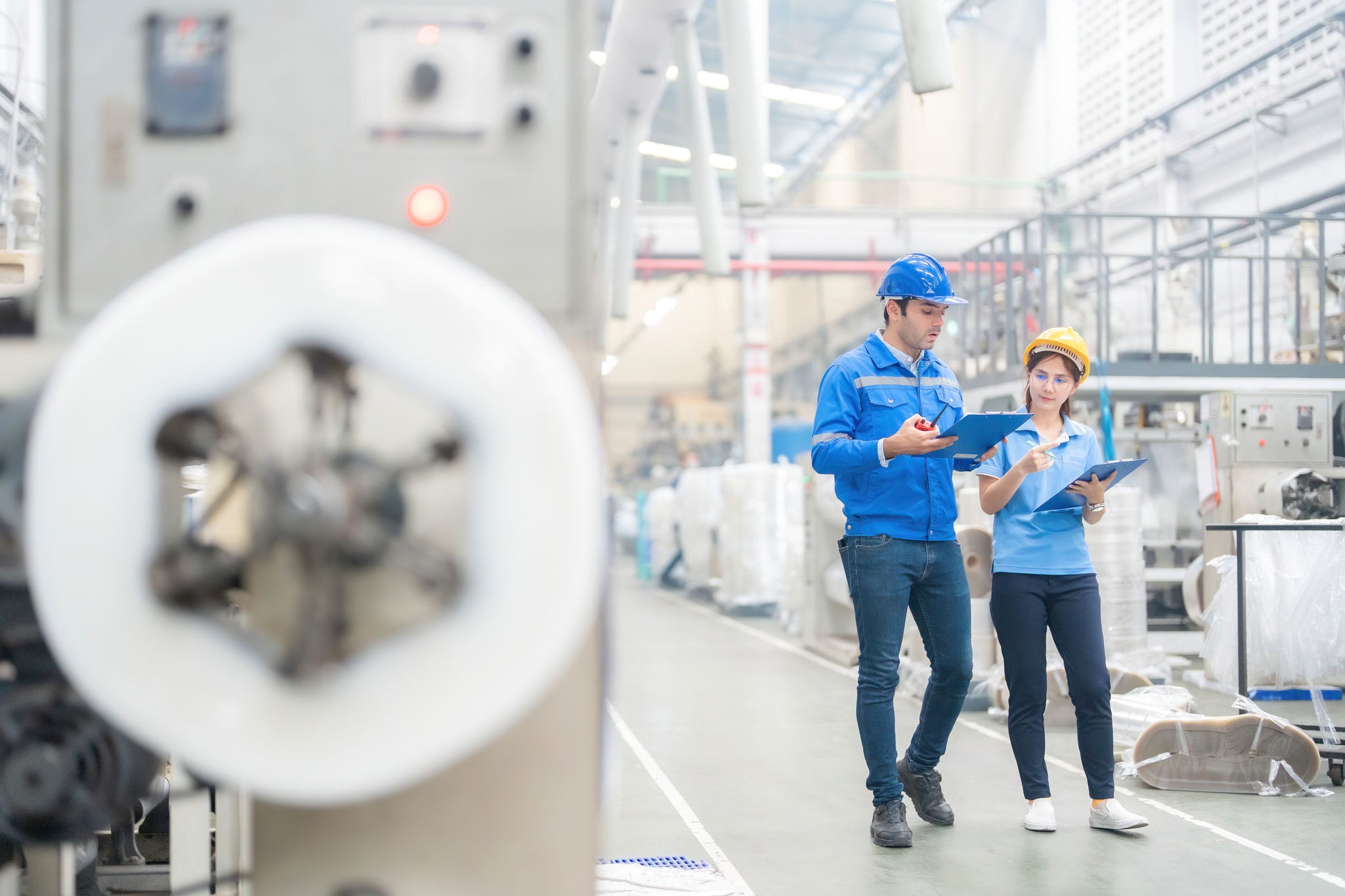 The European male engineer and the Asian female engineer, stationed in the industrial sector, oversee machinery, ensuring top-notch production standards for global market competitiveness.