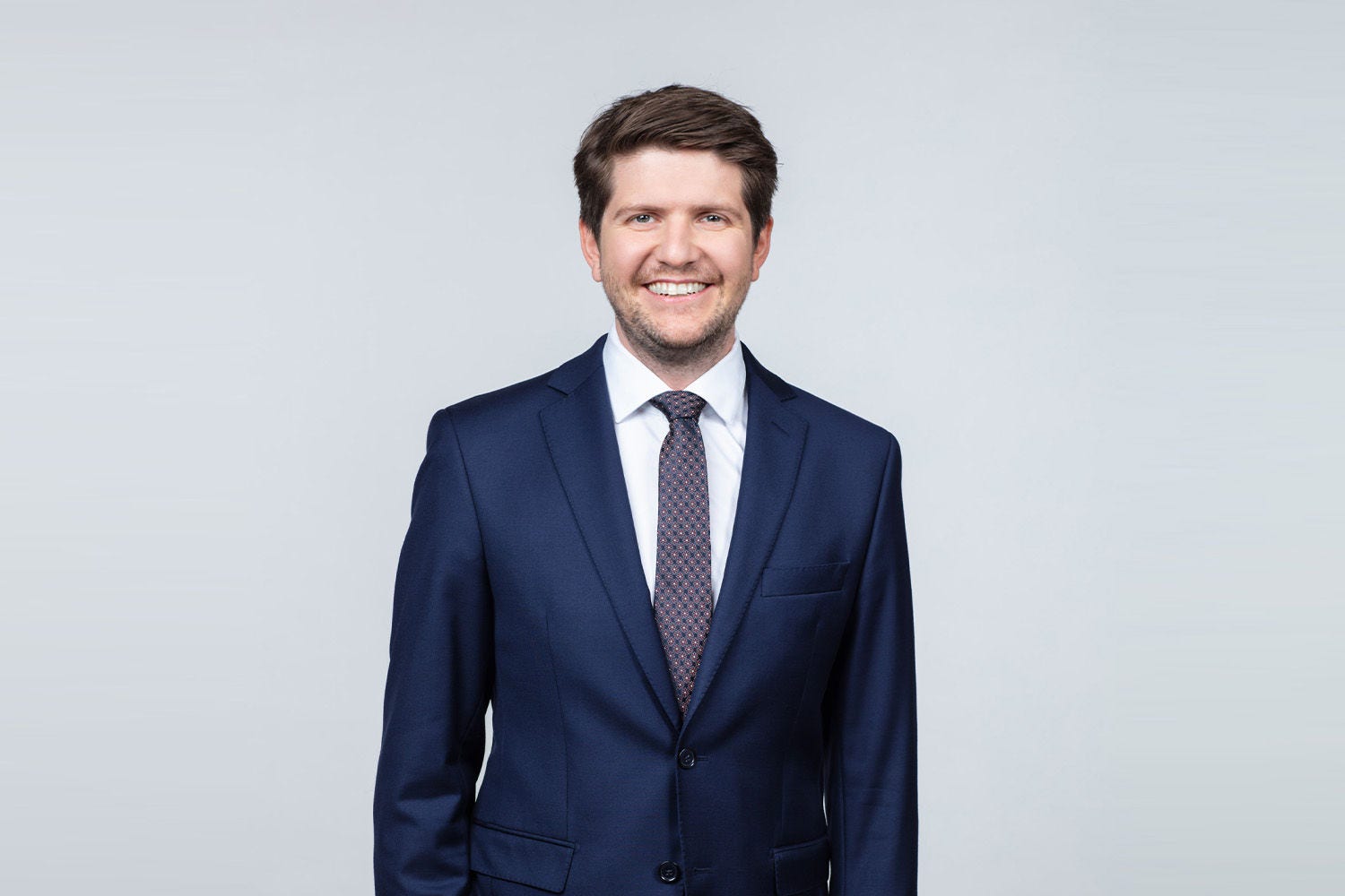 Porträt von Alexander Aschl vor einer hellgrauen Wand