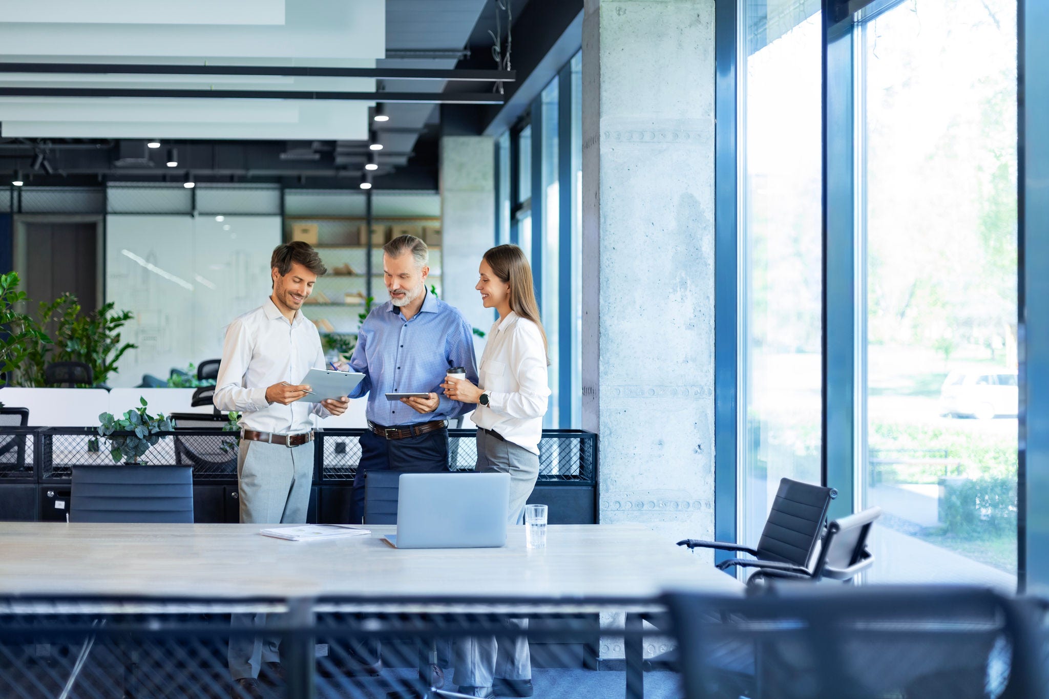 Group of business people standing together and discussing their work and projects, having a team meeting in an office