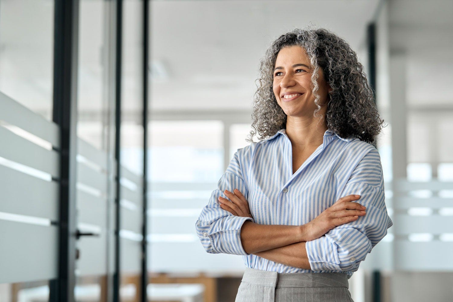 Person crossing arms whilst standing in an indoor office space