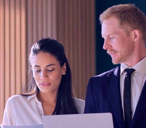 Two people in office collaborating on document Two people in office collaborating on document