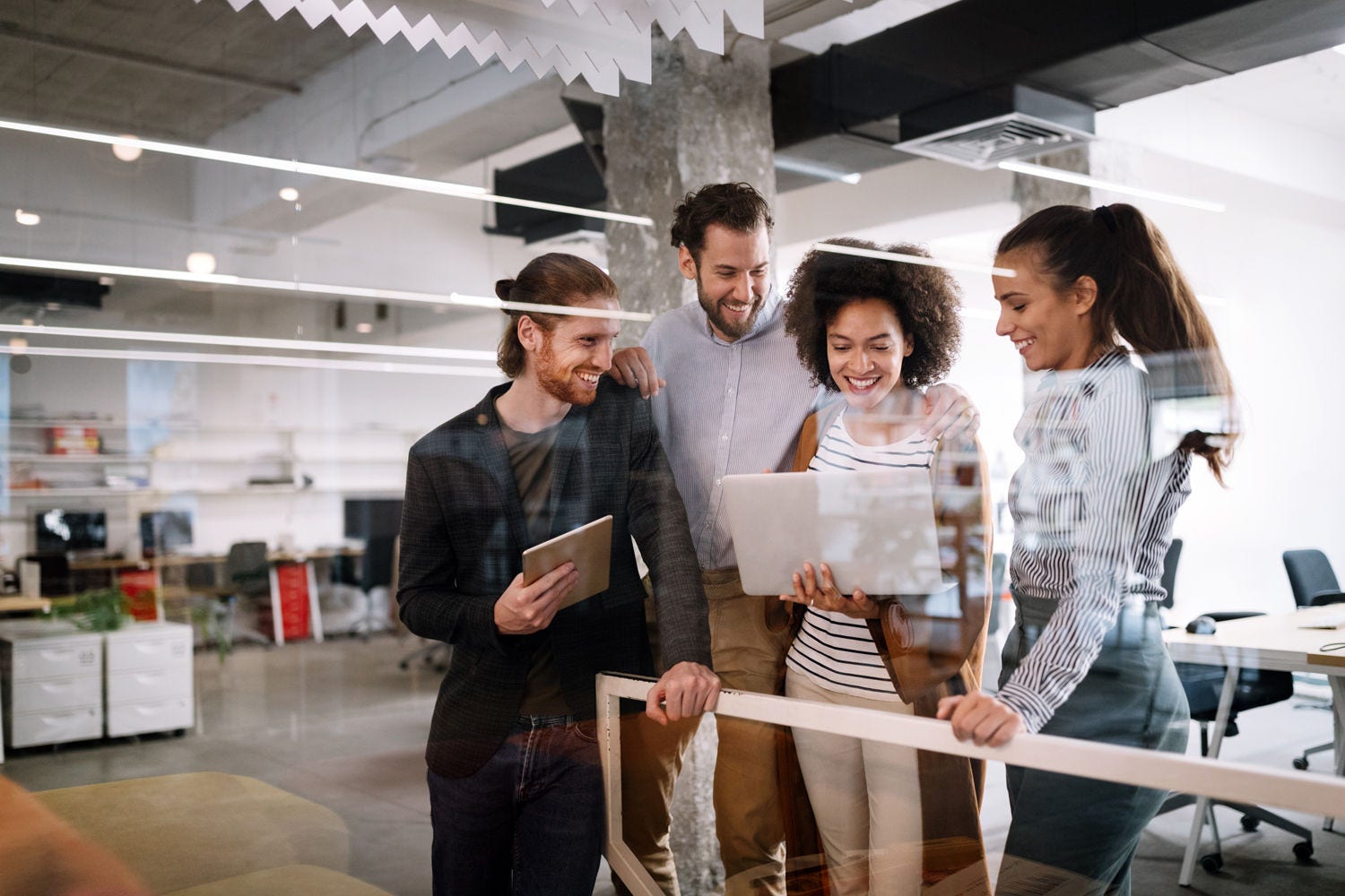 Office colleagues looking at the laptop and smiling