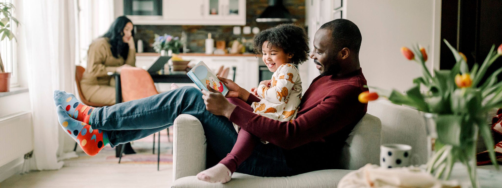 Smiling father teaching daughter sitting on chair in living room
