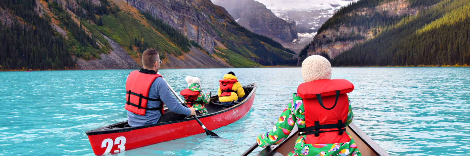 Family canoeing with large mountains