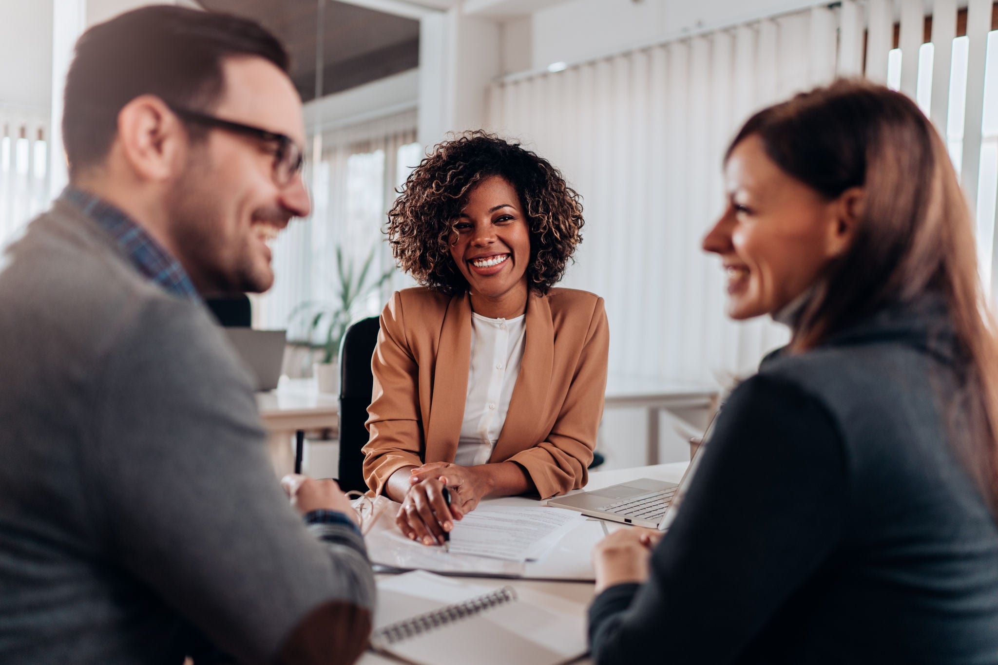 Couple consulting with a female financial manager at the bank about real estate loan