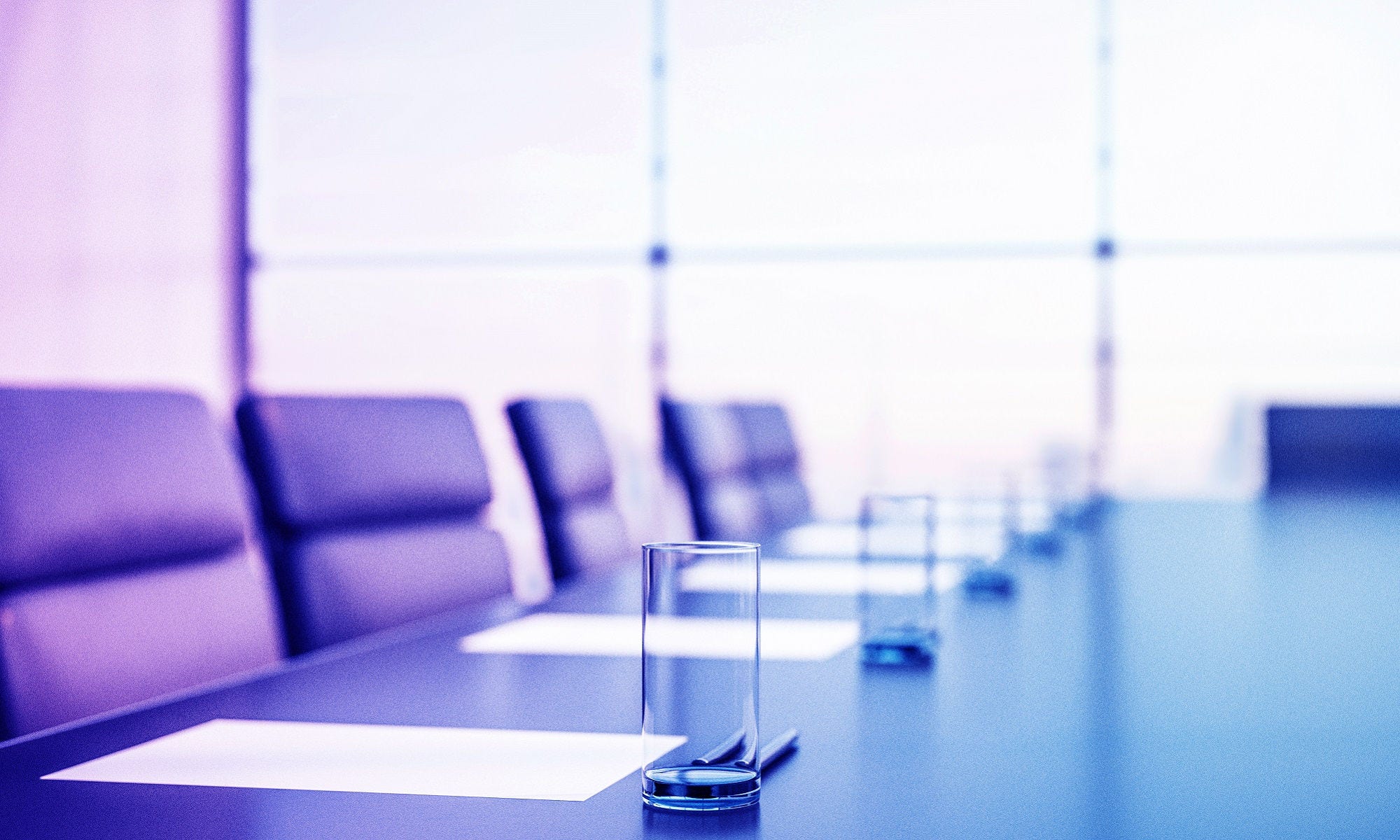 Close up of conference room with glasses of water on the table with papers, armchairs and a large window. 