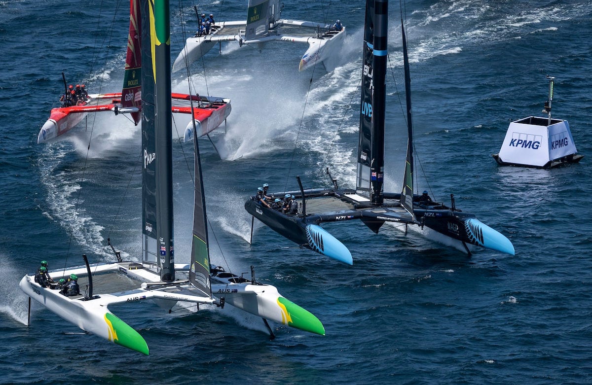 SailGP catamarans racing at high speed on open water.