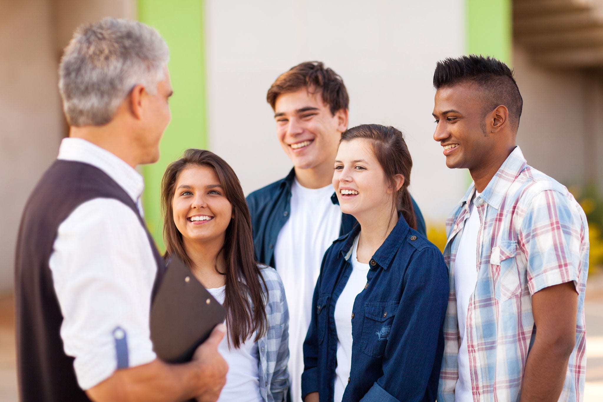 middle aged high school teacher talking to students during break