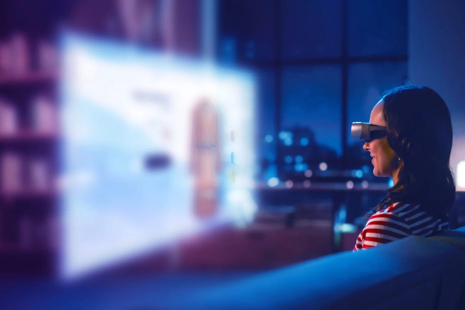 Uma mulher a utilizar um set de Realidade Virtual, o fundo é uma televisão e está desvanecida