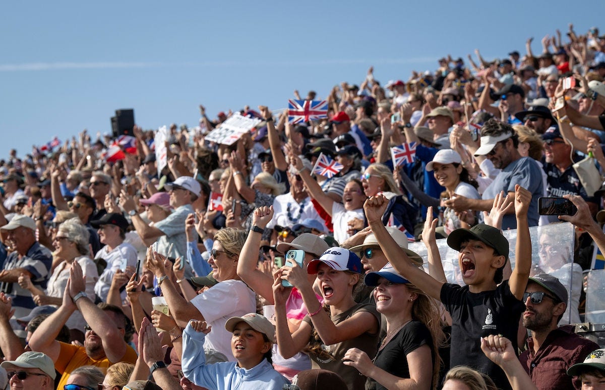 Crowd of spectators cheering at a sailing event.