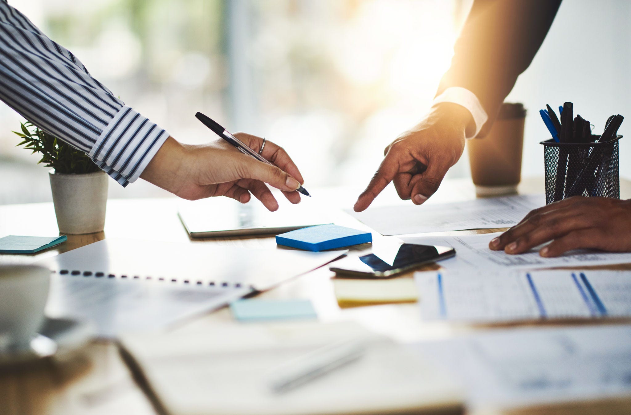 Office, meeting and hands with documents, signature and agreement for business deal or collaboration. Point, info and people with pen for approval, client and legal paperwork for investment on table