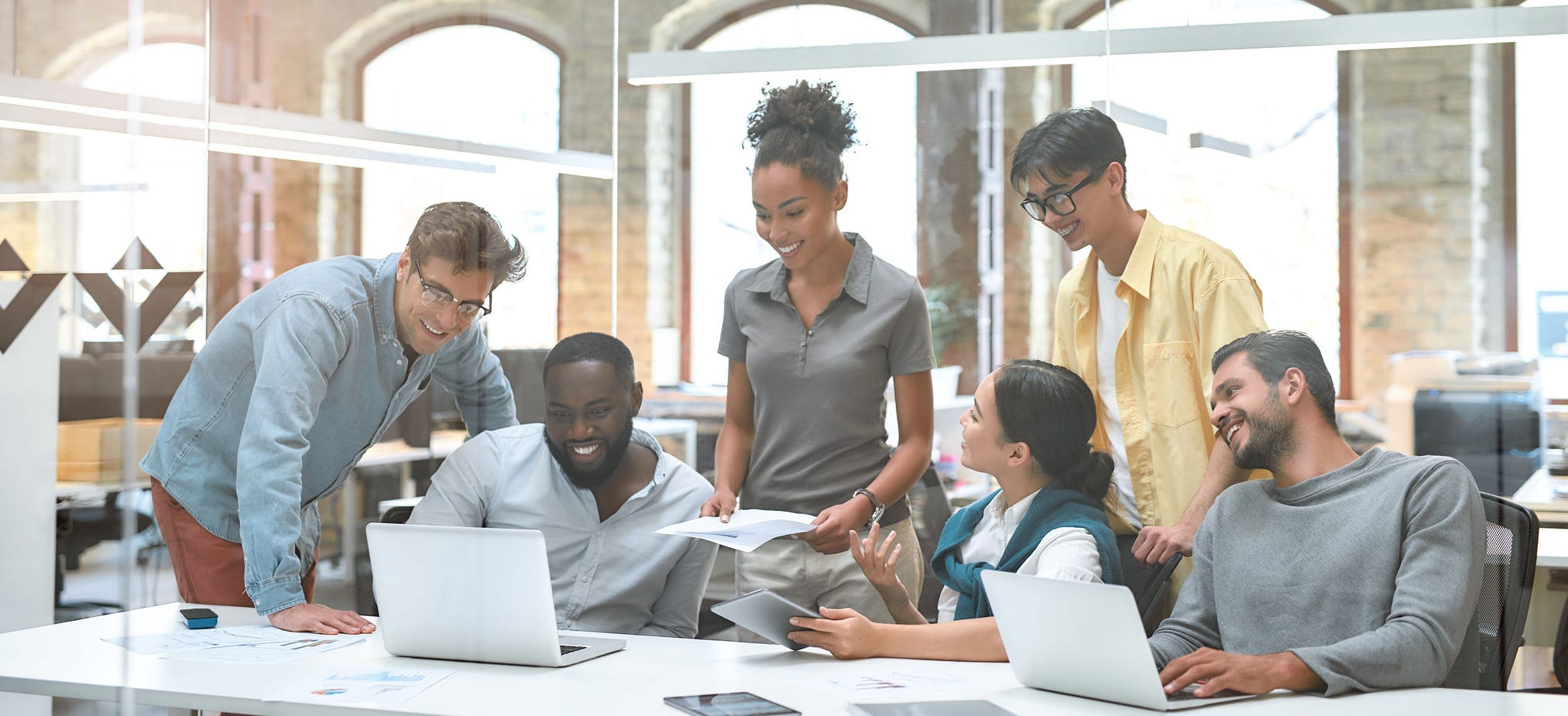Busy working day. Group of business people communicating with each other and discussing project results while sitting together behind the glass wall in the creative office. Office life. Teamwork concept