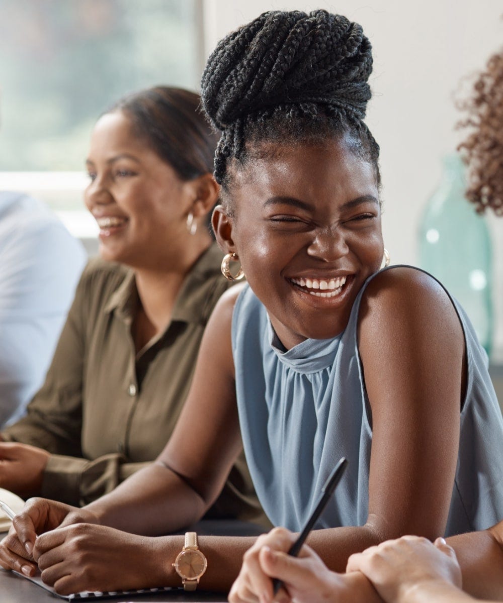 Colleagues sat around a table together laughing, smiling