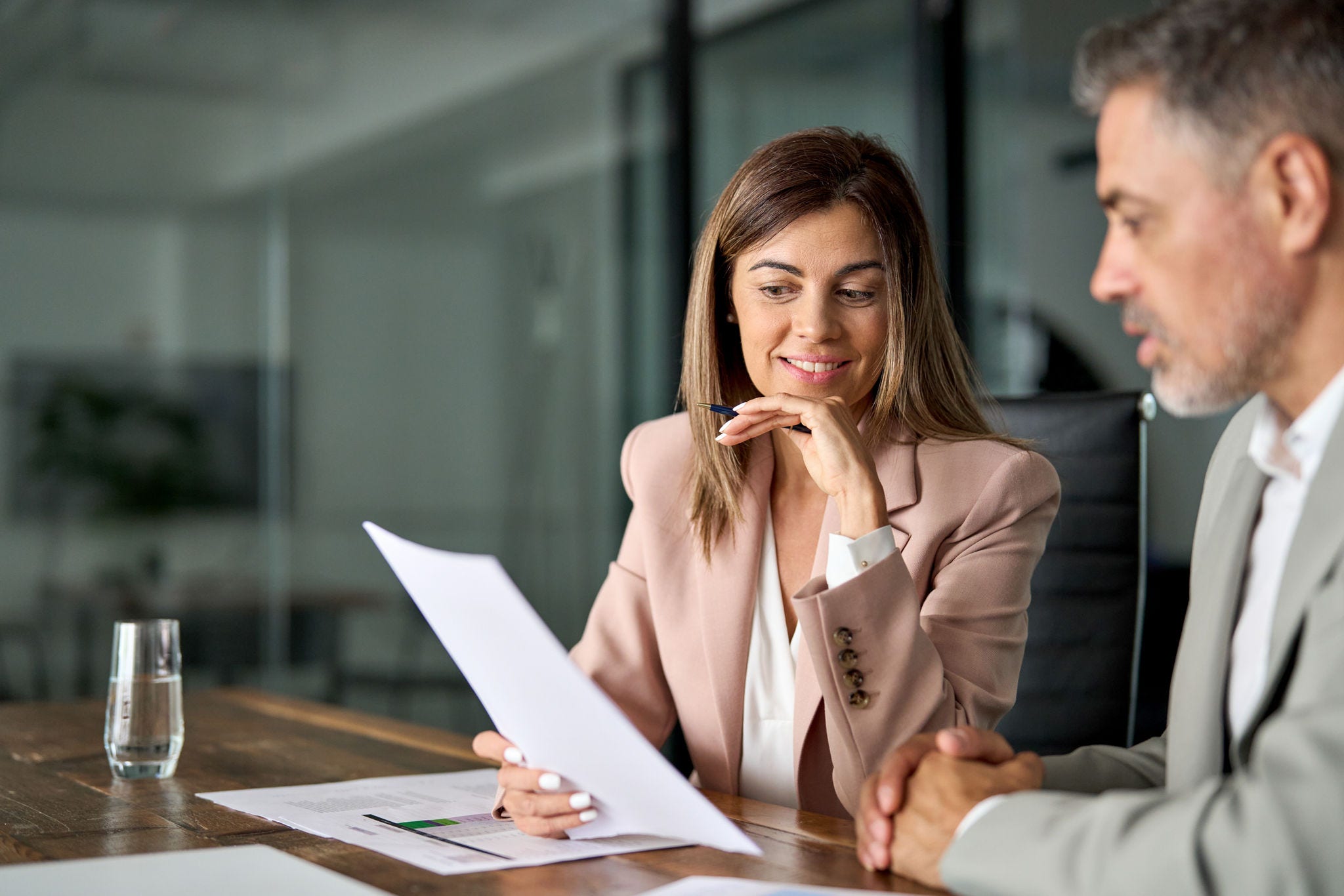 Legal consultancy concept. Business woman lawyer attorney showing document to man client providing advisory services, professionals discussing tax papers working in office at meeting.