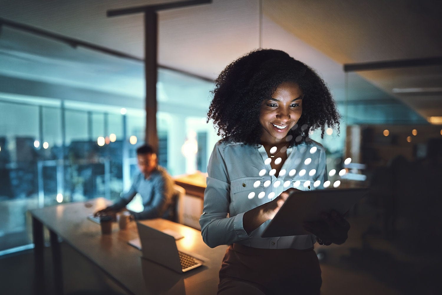 Person using a tablet in a modern office with a digital data overlay.