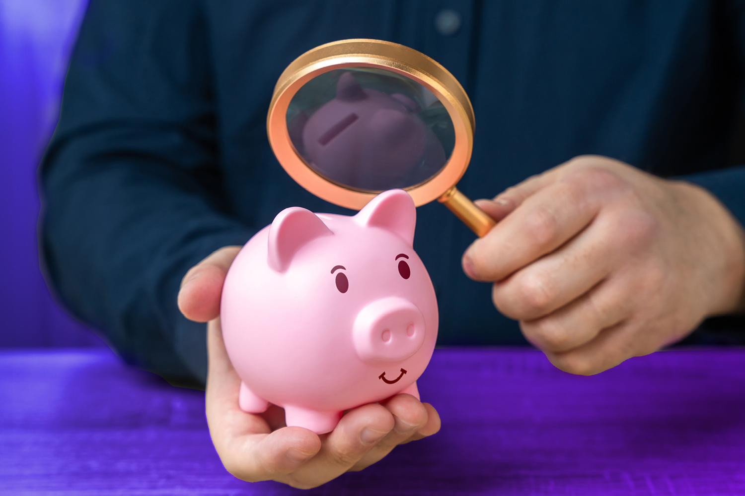 Someone is holding an artificial pig and looking at it through a magnifying glass