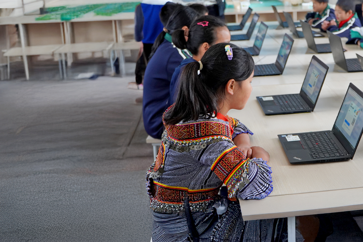 children at a desk looking at laptops