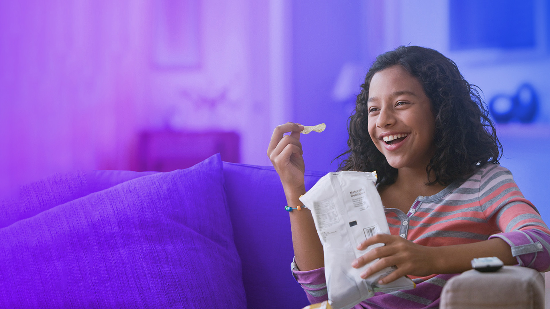 smiling tween sitting on the couch with a snack