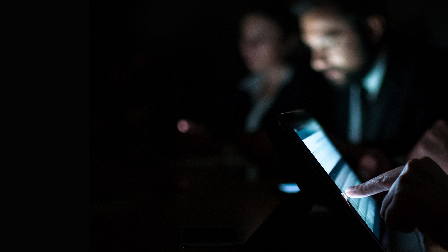 group of people looking at their devices in the dark