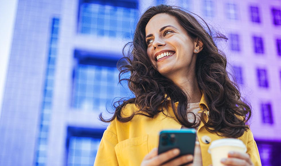 woman with cellphone in hand looking up, smiling